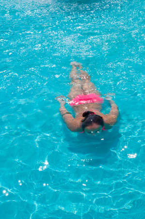 young pretty cute woman or girl in pink bikini swimming under blue pool water at sea or ocean sunny summer outdoor, copy spaceの写真素材