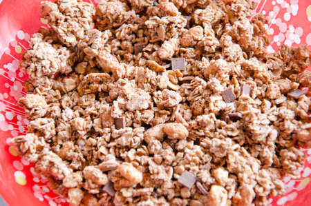 healthy brown tasty crisp morning dry breakfast of chocolate crunch or cereal in red bowl or plate, closeupの写真素材