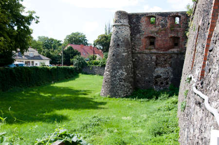 old ruined stony building of broken historical ancient ruins of stone with windows in walls sunny day outdoor with green grassの写真素材