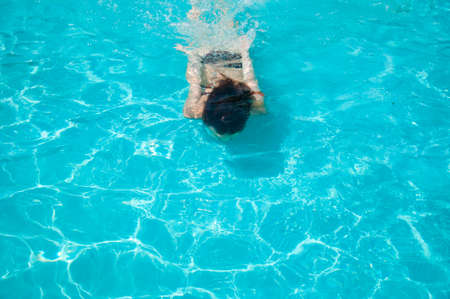 young pretty cute woman or girl in bikini swimming under blue pool water at sea or ocean sunny summer outdoor, copy spaceの写真素材