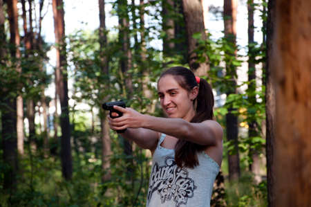Woman with weapon. Gun in hand of shooter. Hunting and education outdoor in forest. Kill and war. Girl shooting from gun., aim and successの写真素材