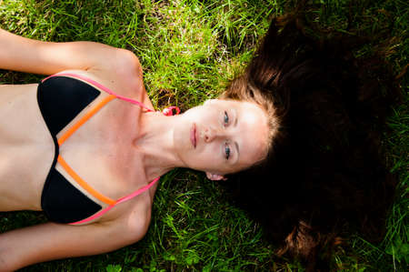 long healthy hair. female hairdresser concept. haircare and health. sexy woman relax on green grass. girl in swimsuit lie on grass outdoor. summer vacation concept. natural and organic cosmetics.の写真素材
