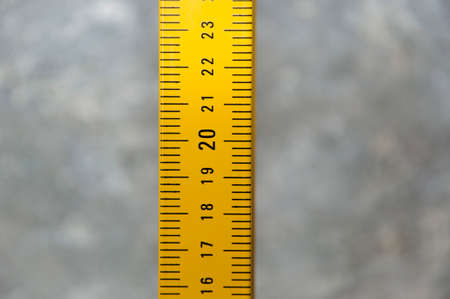 yellow tape measure on grange cement wall background. measuring tape tool. level measuring equipment...
