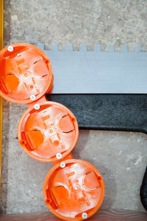 socket box with spatula on damaged wall background. repair and construction. repair tool set. putty knife bushings for sockets.の写真素材