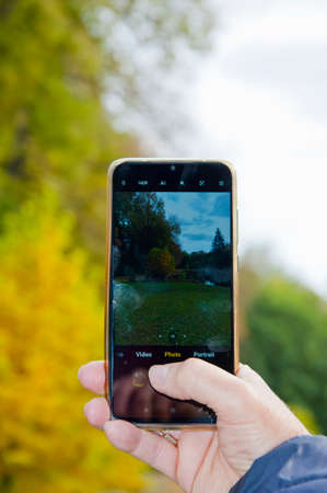 making photo on phone in hand of autumn nature.