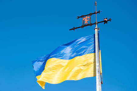 Ukrainian flag with Lviv coat of arms on blue sky background. Ukraine.