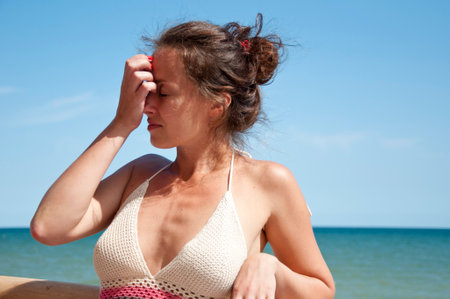 young woman in summer vacation on sea and blue sky background. having headache.の写真素材