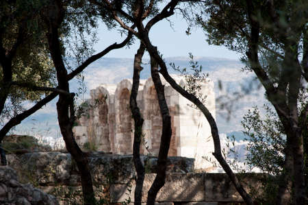 Ancient temple stone arches ruins on background seen through olive trees.の写真素材