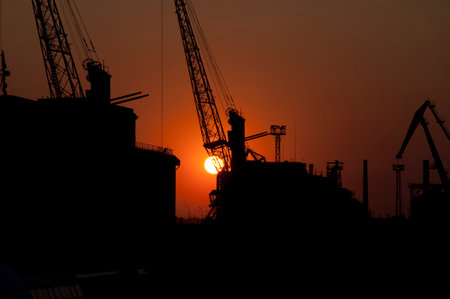 Marine container crane silhouettes in Odesa seaport at sunset sky background.