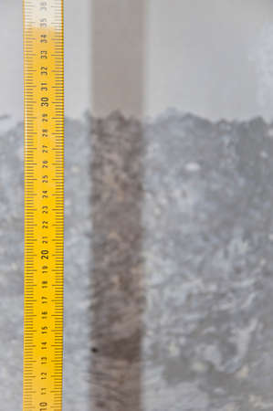 Yellow metal ruler tape-measure measuring tool with millimeter marks and centimeter units cement...