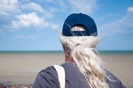 Grey-haired man back view on scenic seascape. Man watching sea horizon. Old man and sea sky...