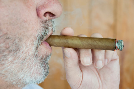 Hispanic senior man enjoying a Cuban cigar, closeup. old Hispanic man smike a Cuban cigar. Cuban cigar. smoking hispanic old man. retirement lifestyle. hispanic old man smoking cuban cigar.の写真素材