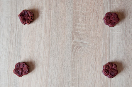 appetizing dog muffins on wooden background. dog birthday. red velvet. paw shaped dog treat. homemade dog biscuit. paw bakery cookie. pet cake. pet treat. pastry food for cat. copy space frame.の写真素材