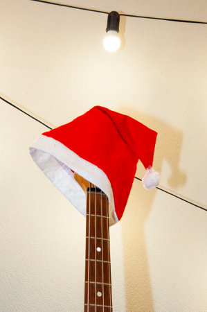 Merry Christmas. Happy New Year. Xmas holiday celebration. New Year eve. Santa Claus hat on guitar. December holiday with music playlist. Decorated Xmas electric guitar. Christmas music playlist.の写真素材