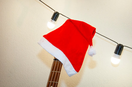 Santa Claus hat on guitar. Holiday with music playlist. Decorated Xmas guitar. Christmas music...