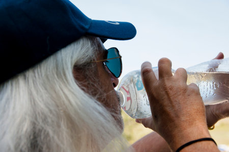 Senior thirsty man feel thirst and drinking water from sport bottle for healthy hydration balance. Drink water in summer heat.の写真素材