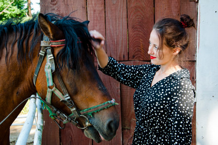 Woman with horse in stable at countryside ranch. Girl horse rider in summer outdoor. Equestrian and horseback riding. Horse stallion equine with woman girl. Countryside ranch. Ranching heritage.の写真素材