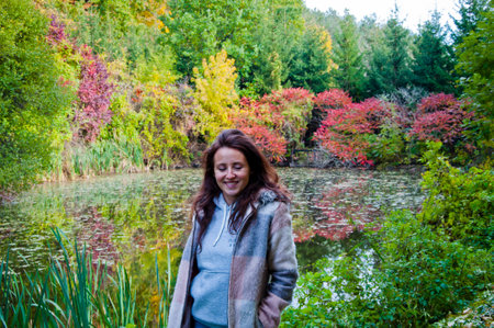 Girl in autumn style at pond. Girl and lake pond. Autumn girl outdoor in park. Central park in fall season. Fall woman in park. Autumn woman outdoor. Woman in fall nature. Colorful trees.の写真素材