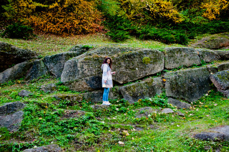Girl in autumn style. Girl on rocky landscape full length. Autumn girl in park. Central park...