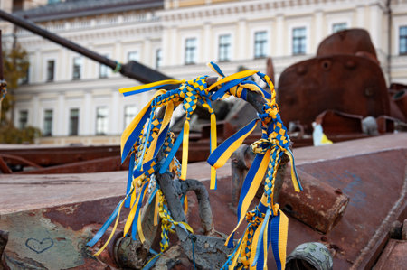 Handmade friendship bracelet macrame from moulinet ribbon of blue yellow colors of Ukrainian flag on destroyed military vehicle. Military equipment fair. Independence day of Ukraine 2024.の写真素材