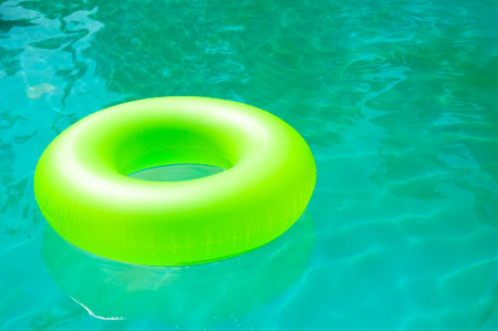 Relaxing at the pool. Summer resort vacation. Recreation. Copy space. Inflatable ring in swimming pool. Swimming bright ring. Fun in the pool. Inflatable ring at poolside. Summer vacation.の写真素材