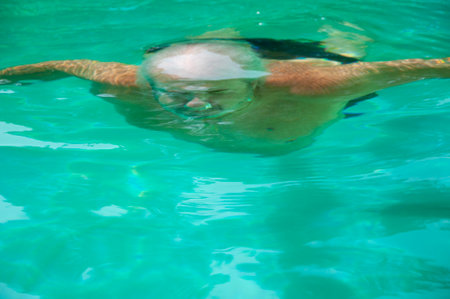Summer vacation. Pool dive by person man diver. Man diver diving in water of swimming pool and swim underwater. Vacation on summer. Diving in swimming pool. Crystal-clear diving waters.の写真素材