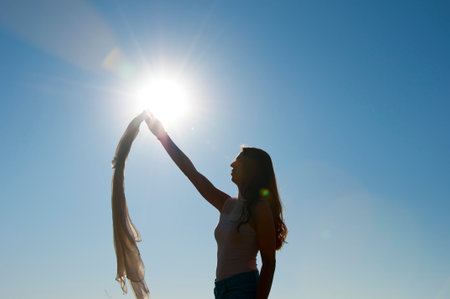 Ballerina dancing with silk fabric. Ballet dancer in fluttering waving cloth outdoor. Gymnast girl dancing with flying fabric in backlit. Flying fluttering fabric and woman silhouette in the sun.の写真素材