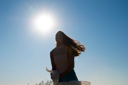 Sense of freedom. Lifestyle grace. Young girl with fabric in backlit. Woman silhouette in the sun. Backlit silhouette of woman or girl on summer vacation. Well being and inspiration. Funny and free.の写真素材