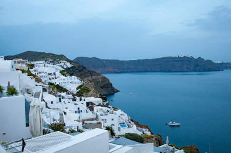 Travel destination. Touristic spot and tourism. Traveling. Santorini island architecture landscape in evening. Banner. Night touristic city with sea and volcanic mountainの写真素材