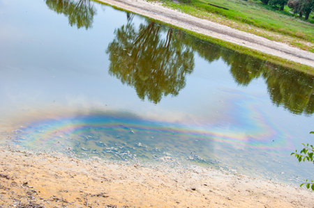 Nature and ecology. Environmental pollution. Polluted environment. Water treatment failure. Industrial waste discharge. Chemical runoff. Oil and gasoline stains. Lake with gasoline stains on water.の写真素材