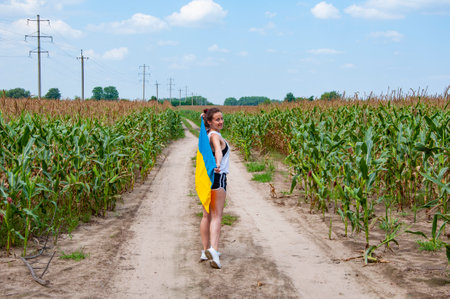 Girl covered with Ukrainian flag in field. Flag of Ukraine. National flag patriotic girl. Independence day. Patriotic symbol. Patriotism. Ukrainian flag memorial day or 24th of August, liberty.の写真素材