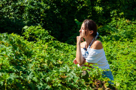 Woman sitting in lush green forest. Tropical beauty. Relaxation retreat. Young girl in pearl necklace, green white. Nature therapy. Copy space.の写真素材