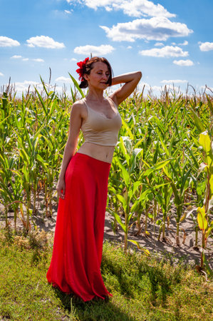 Flamenco dancer. Summer fashion. Spanish girl in vibrant red skirt and flower in hair. Countryside scene. Folklore girl. Ethnic and folk. Young woman in cornfield under blue sky. Organic life.の写真素材