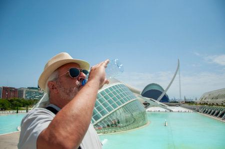 City of arts and sciences in Valencia, Spain. Travel destination. Man senior tourist drinking water at Valencia architecture landmark. Touristic architecture sightseeing. Travel man in Valencia.の写真素材