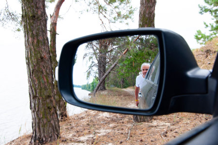 Reflection in rear view mirror of car. Retired old man driver. Senior man reflected in mirror...