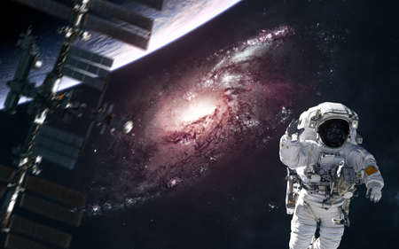 A red spiral galaxy somewhere in deep space. Astronaut, blurred space station, planet. Science fiction. Elements of this image furnished by NASAの写真素材