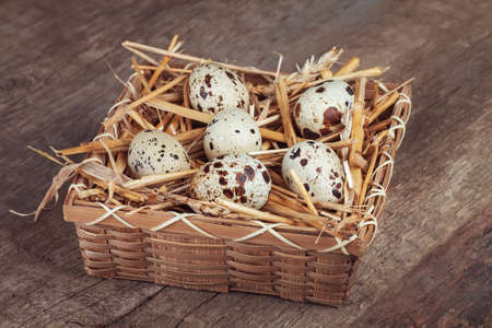raw quail eggs in a wicker basket on wooden table