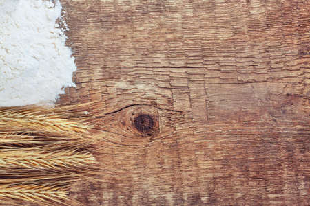 ears of wheat and flour on wooden background card with place for textの写真素材