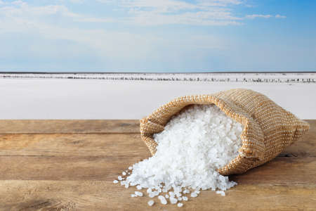 sea salt in bag. Crystals of salt in sack on table with salty lake in the background. Bag of sea salt produced on farmの写真素材