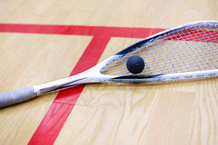 squash racket and ball on the wooden background. Racquetball equipment. Squash ball and squash racket on the court next to a red line. Photo with selective focusの写真素材