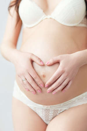 pregnant belly and heart from the handsの写真素材