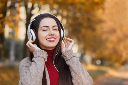 Girl listening music in autumn parkの写真素材