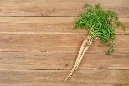 Fresh parsley roots with leaves on wooden table with copy space. Top view