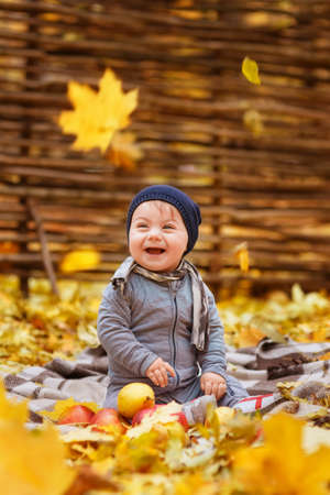 baby girl laughing and playing with golden leavesの写真素材