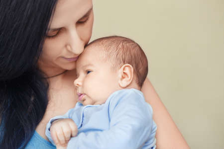 mother holding and kissing newborn babyの写真素材
