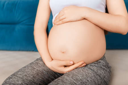 closeup pregnant woman touching her belly