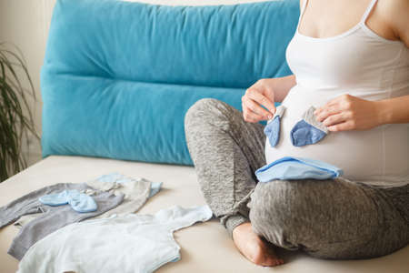 pregnant woman preparing baby clothesの写真素材