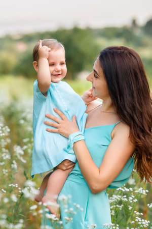mother holding little daughter on summer meadow