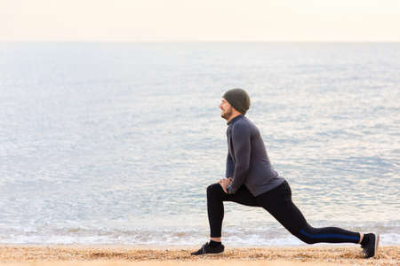 Man doing stretch exercises on the sea beach