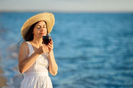 woman holding glass of wine by the sea